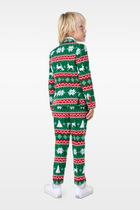 Zaļš svētku uzvalks ar baltām ziemeļbriežiem, sniega pārslām un Ziemassvētku eglītēm, kopā ar sarkaniem un baltiem svītrām akcentiem un baltām kedām.