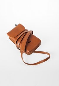 Braune Leder-Crossbody-Tasche mit Klappenverschluss, Reißverschlussfach, verstellbarem Riemen und geprägtem Logodetail. Glatte Textur.