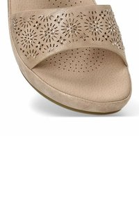 Sándala abierta beige con una correa perforada estampada y adornos de strass, plantilla de textura suave y forma redondeada.