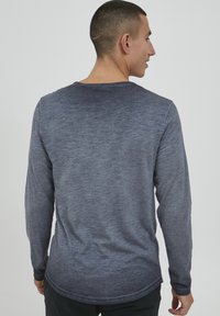 Langermet skjorte i en gradient fra mørk til lys blå, laget av teksturert stoff med rund hals og avrundet nederkant.