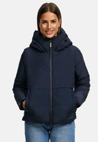Donkerblauwe pufferjack met een hoge capuchon, ritssluiting aan de voorkant en twee zijzakken; heeft een gladde textuur en minimale naden.