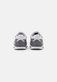 Gray suede and mesh sneakers with white accents, featuring a cushioned sole and padded collar, shown from the rear. Red logo detail on heel.