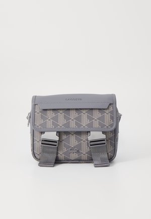 Bolso bandolera gris con patrón geométrico, hecho de material sintético, con solapa plegable, herrajes plateados y correas ajustables.