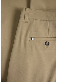 Beżowe bawełniane spodnie z obszytym pasem, z tylną kieszenią ozdobioną niebiesko-białym paskiem i zapięciem na guziki.