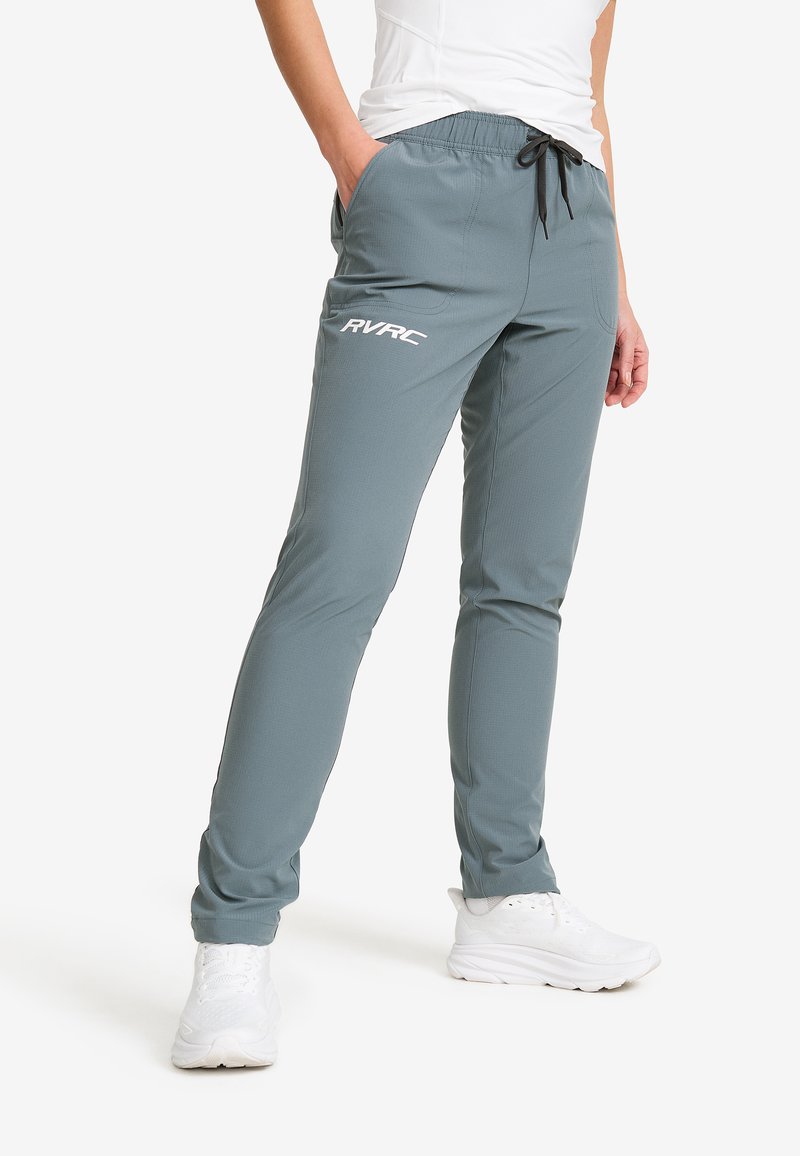 Hellgraue Sporthosen mit elastischem Bund, Kordelzug, seitlichen Taschen und weißen Logoplaketten. Tailored Fit mit glatter Textur.