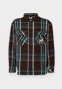 Brown plaid flannel shirt with dark green, blue, and white stripes; features two front pockets and button closure. Textured fabric.