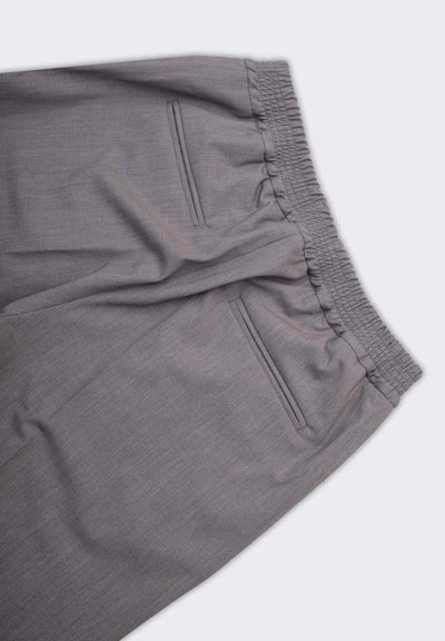 Pantaloni grigi con cintura elastica, dotati di tasche frontali piatte e un tessuto liscio e strutturato. Design sartoriale con una silhouette moderna.