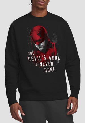 Schwarzer Sweatshirt mit einem grafischen Druck, der eine Figur in einer roten Maske und den Text "DAS WERK DES TEUFELS IST NIE GETAN." zeigt. Weicher Stoff, Rundhalsausschnitt.