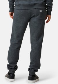 Mörkgrå sweatpants i bomullsmix, med avslappnad passform och en bakficka med etikett. Benvidden är rullade vid anklarna.