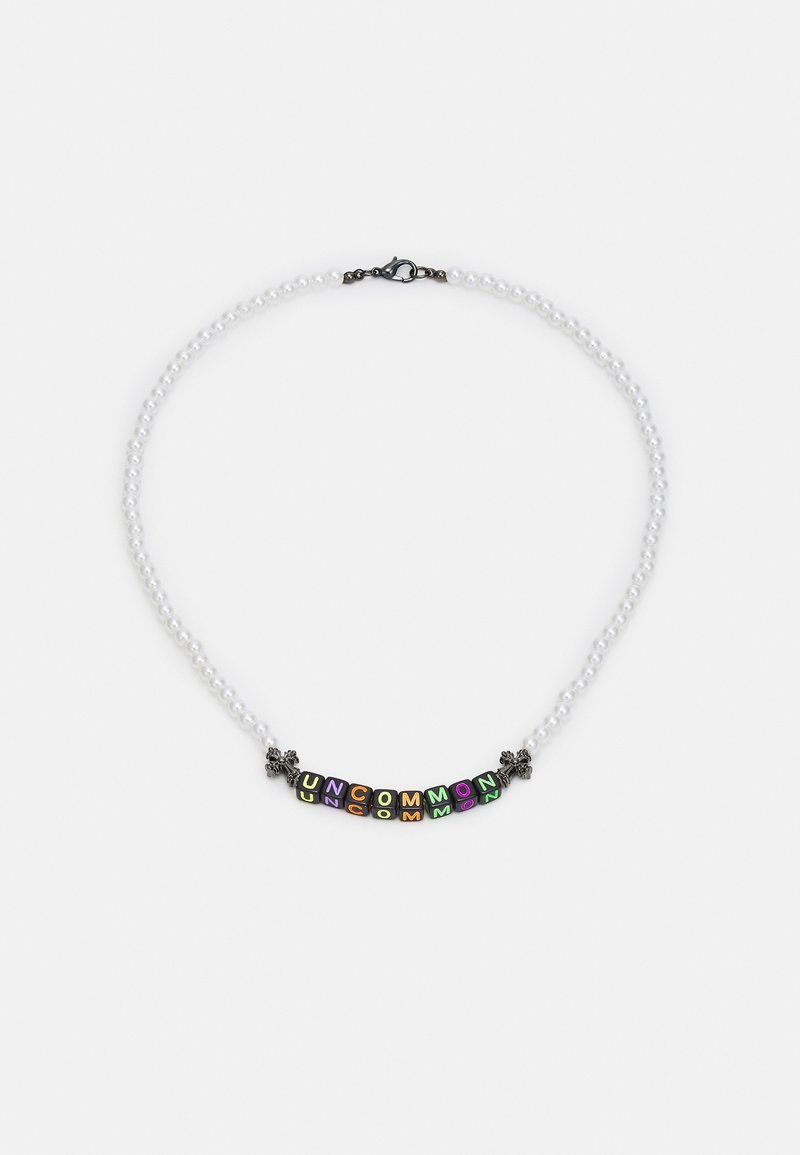 Collier avec des perles rondes blanches et des perles carrées multicolores formant "UNCOMMON" en deux rangées, avec de petits accents floraux noirs.