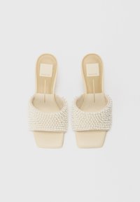 Open-toe slide sandals with a cream base and a textured strap embellished with white pearls. Flat sole and minimal design.