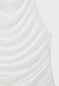 White fabric with horizontal gathered ruffles creating a textured, layered pattern on a light background.