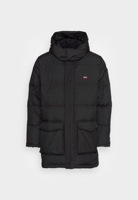 Svart puffjacka med huva, med dragkedja framtill, två stora framfickor och en logopatch på bröstet. Slät, isolerande textur.