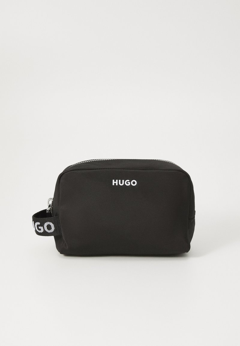 Fekete nejlon fürdőtasak téglalap alakú, ezüst cipzárral és egy márkás fogantyúval, amelyen fehér betűkkel "HUGO" felirat található.