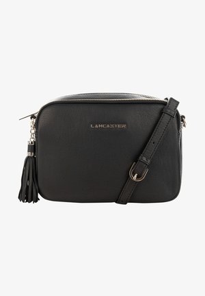 Sac bandoulière en cuir noir avec fermeture éclair, bandoulière amovible et un pompon décoratif. Détails du logo métallisé.