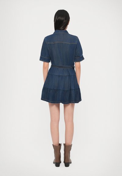 Džínové šaty s krátkymi rukávmi, viacvrstvovou sukňou, pásom v páse a viditeľným prešitím. V tmavomodrej farbe s hladkou textúrou a ležérnym dizajnom.