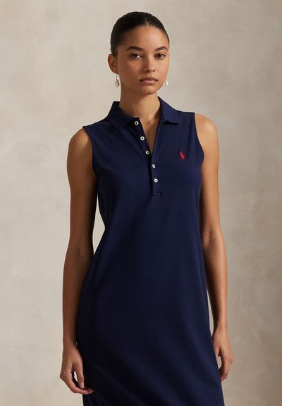 Navy sleeveless polo dress with a fitted silhouette, three-button placket, and red logo detail on the chest. Smooth fabric texture.
