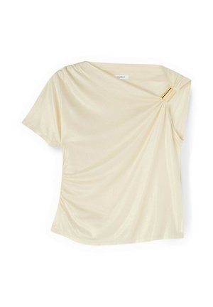 Crèmekleurige blouse met korte mouwen en een asymmetrische halslijn, samengebonden en vastgezet met een gouden rechthoekige gesp op de rechterschouder.