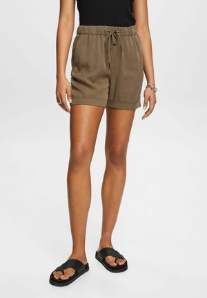 Olivgrön, lätta shorts med elastisk midja, snörning, två sidofickor och uppvikta ärmar. Bärs med svarta sandaler.