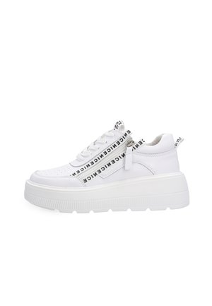 Baskets blanches à plateforme avec semelle épaisse, texte noir sur les lacets et la languette de la fermeture éclair, fermeture éclair latérale et languette à l’arrière du talon et à la languette.