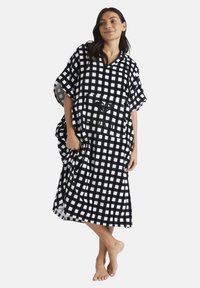 Black and white checkered beach cover-up made of soft fabric, featuring short sleeves, a V-neckline, and a front pocket with logo detail.