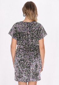 Schwarzes, kurzes Kleid mit floralem Muster in Pink, Grün und Weiß. Lockere Passform, kurze Ärmel und strukturierter Stoff, reicht bis über das Knie.