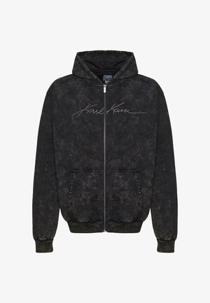 Mustahdudhu sidirik mweusi wenye muonekano wa kutu na rangi iliyoondolewa. Ina kofia, mifuko ya pembeni, na "Karl Kani" imeandika kwa rangi nyekundu kwenye mbele.