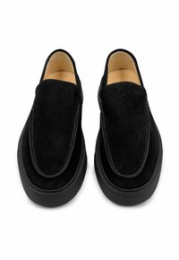 Zwarte suède instapschoenen met ronde neus, contrasterende stikseldetails en een zwart geribbelde rubberen zool. De binnenkant is voorzien van een beige voering.