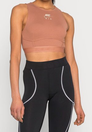 Crop top de sport marron à texture côtelée, logo Nike AIR sur la poitrine, associé à des leggings noirs avec des coutures d'accent blanches.