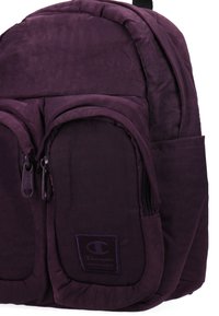 Zaino viola realizzato in tessuto testurizzato, con due tasche frontali con cerniera e una patch con il logo. Ha spallacci imbottiti per il massimo comfort.
