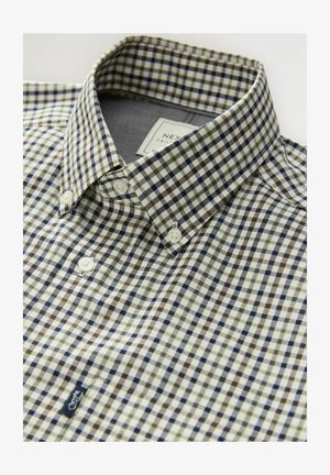 Chemise à carreaux avec un mélange de couleurs marine, marron et crème, dotée d'un col classique et d'une texture subtile. Étiquette visible.