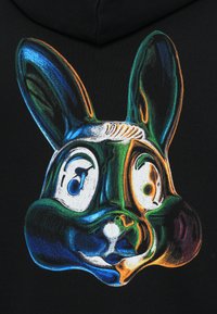 Spalvingas, stilizuotas triušio grafikas ant juodo audinio fono; turi dideles ausis, ryškius akis ir lygų paviršių.