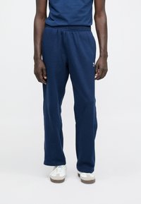 Tmavomodré tepláky majú elastický pás, rovné nohavice a malú logo na boku, vyrobené z mäkkého bavlneného zmesi.