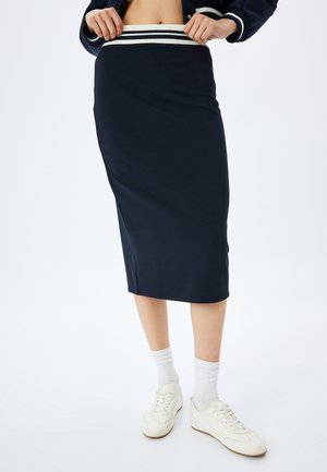 Gonna midi blu navy realizzata in tessuto elasticizzato, con una cintura a strisce bianche in contrasto. Progettata con una silhouette aderente e con spacchi laterali.