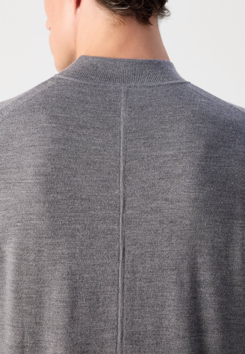 Grauer Strickpullover mit hochgeschlossenem Kragen und einer zentralen Nahtdetails auf der Rückseite, aus weichem, feinstrukturiertem Material gefertigt.