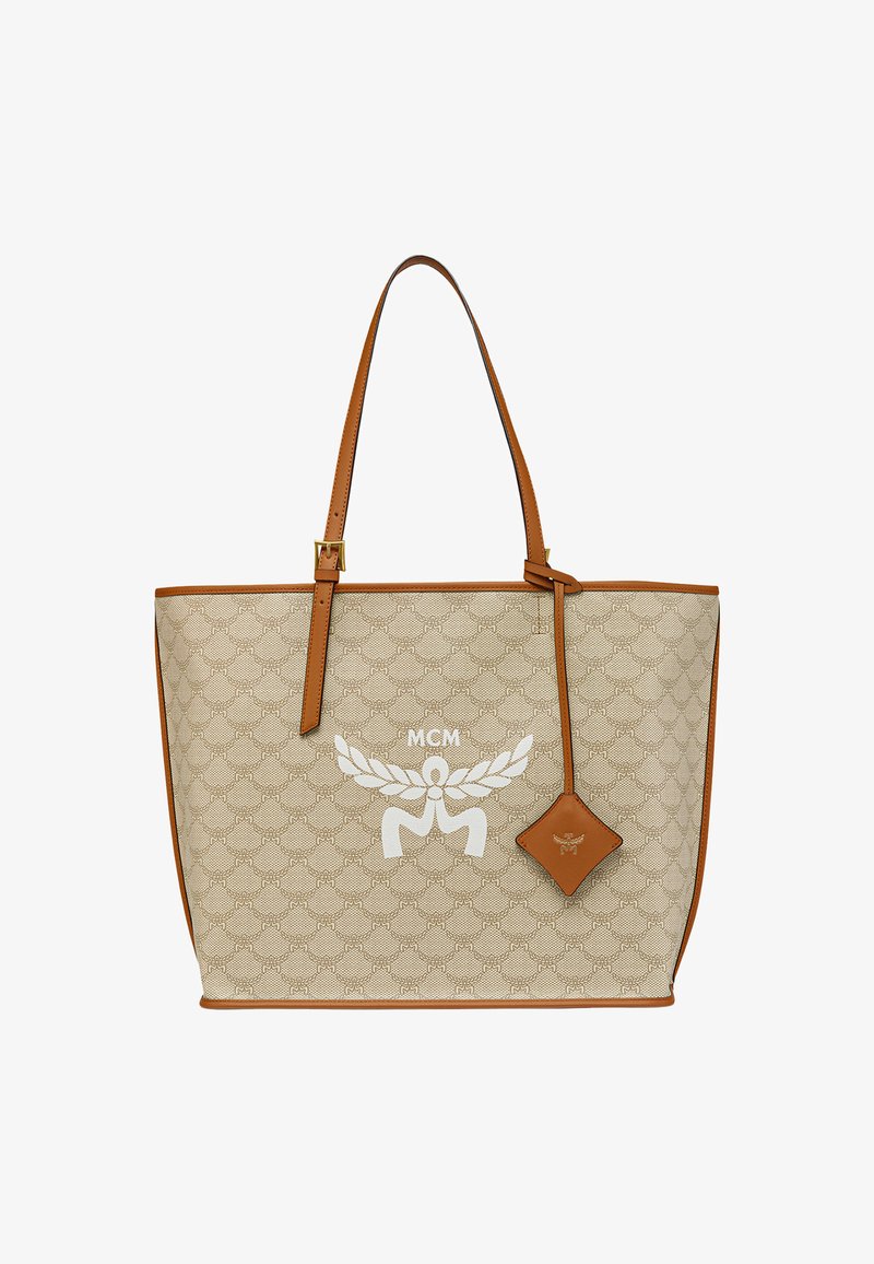 Sac fourre-tout beige avec des garnitures en cuir, présentant un motif texturé, des matériels en or et un logo blanc. Sangles réglables en brun et un détail de breloque.