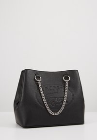 Sac cabas en cuir noir à surface texturée, avec poignées en chaîne argentée et logo en relief bien visible à l'avant.