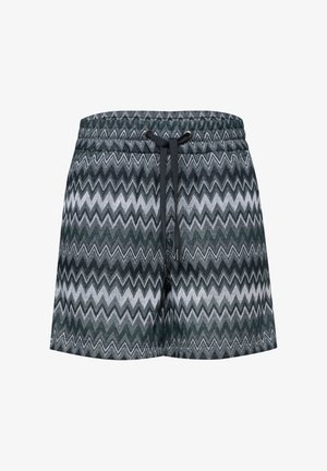 Bañador corto de hombre con patrón de zigzag blanco y negro y cintura ajustable con cordón negro sobre fondo liso.