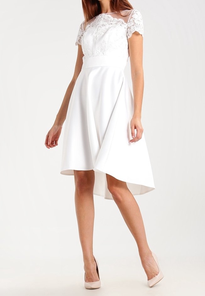 Bílé šaty s krátkými krajkovými rukávy, přiléhavým korzetem a asymetrickou suknią ve stylu skater. Hladká textura s mírným leskem.