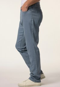 Pantalones de mezclilla azul claro con corte recto, bolsillos laterales y traseros, y una textura suave, combinados con zapatillas blancas con cordones.