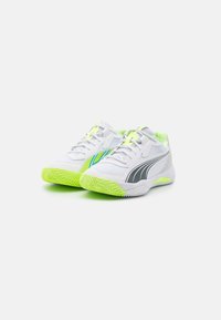 Zapatillas deportivas blancas con acentos grises, detalles verdes y suela de goma texturizada. Parte superior de malla para transpiración, con un logo estilizado.