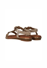 Beige sandaal gemaakt van synthetisch materiaal met een gestructureerde band, decoratieve edelsteensieraden en een gevoerde, met patroon bedekte voetbed. Bruine zool.