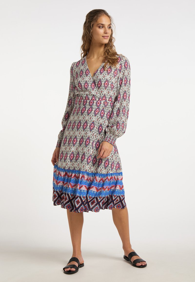 Rochie cu mâneci lungi, cu un model, având un decolteu adânc în V, talie elastică și un tiv voluminos în nuanțe de roz, albastru și alb pe un fundal gri.