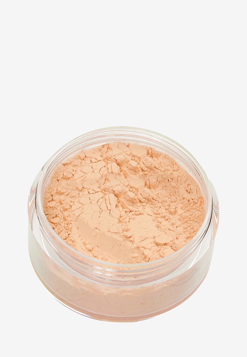 Polvere libera in un contenitore trasparente, caratterizzata da un colore pesca chiaro e una superficie texturizzata, con crepe visibili sulla polvere.