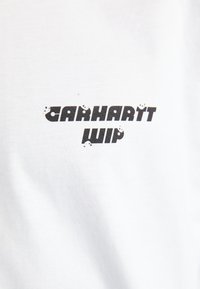 Witte katoenen T-shirt met het "Carhartt WIP"-logo in vetgedrukte zwarte letters, met lichte verwering rond de randen.
