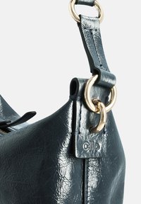 Donkerblauwe leren handtas met een gestructureerd oppervlak, voorzien van goudkleurig beslag, een clip en een brede riem met stikseldetails.