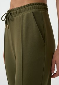 Groene sweatpants van zachte stof, met een elastische tailleband, een trekkoord met gouden accenten en zijzakken.