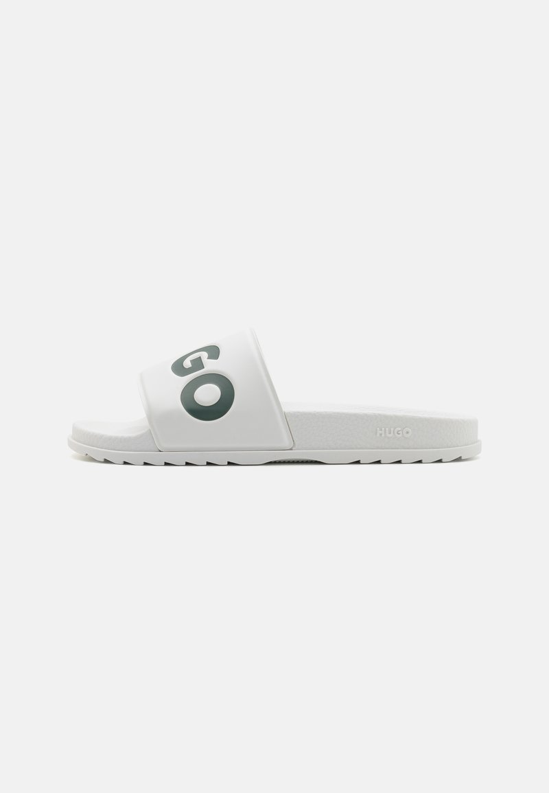 Hvid slide sandal med en bred rem, der har et grønt "GO" logo. Tekstureret fodseng og hvid gummisål med zigzag mønster for godt greb.