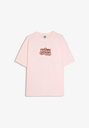 Lyserød kortærmet T-shirt med brun "Welcome to Animal Crossing" logo centreret på brystet.