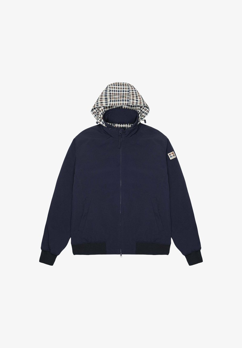 Giacca blu navy con zip frontale, polsini elastici, due tasche laterali e una fodera a scacchi nel cappuccio. Presenta un emblema sulla manica.